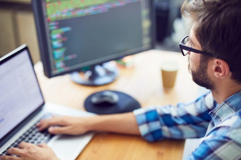 Close up shot of a young software developer, programmer  working at his desk