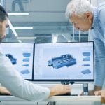 Industrial Designer Has Conversation with Senior Engineer While Working in CAD Program, Designing New Component. He Works on Personal Computer with Two Monitors.