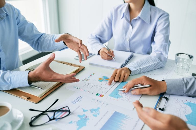 Close-up image of business team talking about charts and graphs at the meeting