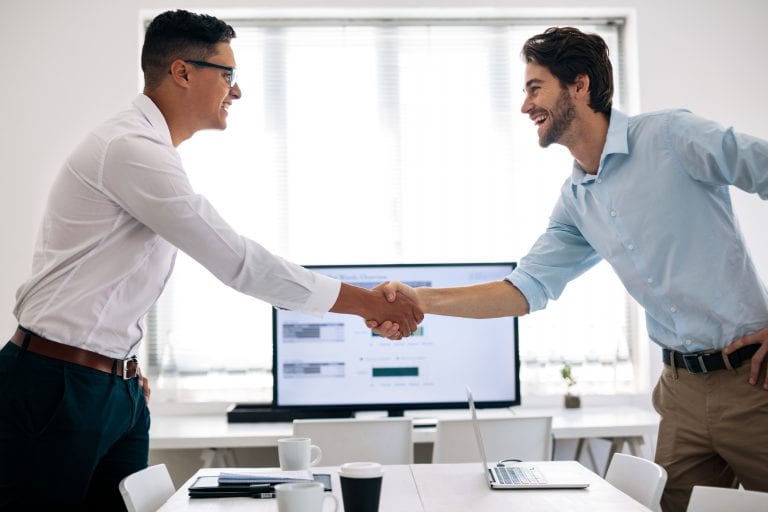 Business colleagues shaking hands in the conference table. Happy businessmen greeting each other in the meeting room.