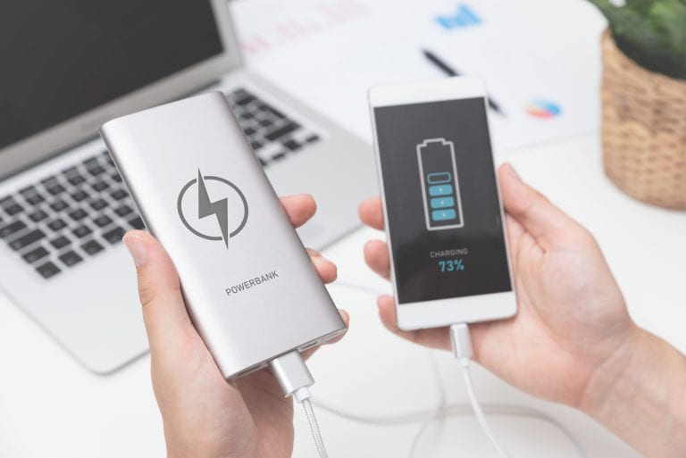 Man connecting USB charger to smart phone. Power bank, mobile phone battery on desk concept