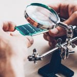 Electronics expertise. Microcircuits, magnifier Technician examining components