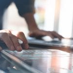 Business analysis and technology, financial investment concept. Business man reviewing marketing report on digital tablet and laptop computer with modern digital computer dashboard virtual screen in office, close up